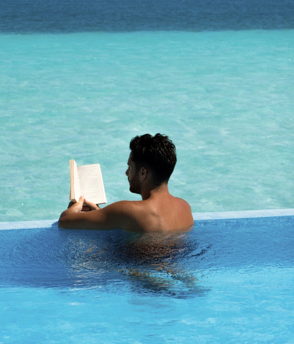 A guest reading a book in a private pool at Kuda Villingili Resort Maldives