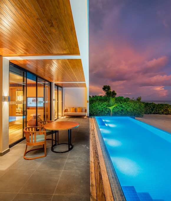 The pool and exterior of Four Bedroom Beach Pool Villa at Kuda Villingili Resort Maldives in the evening