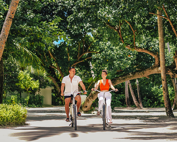 A couple rides bicycles along a scenic path in Kuda Villingili