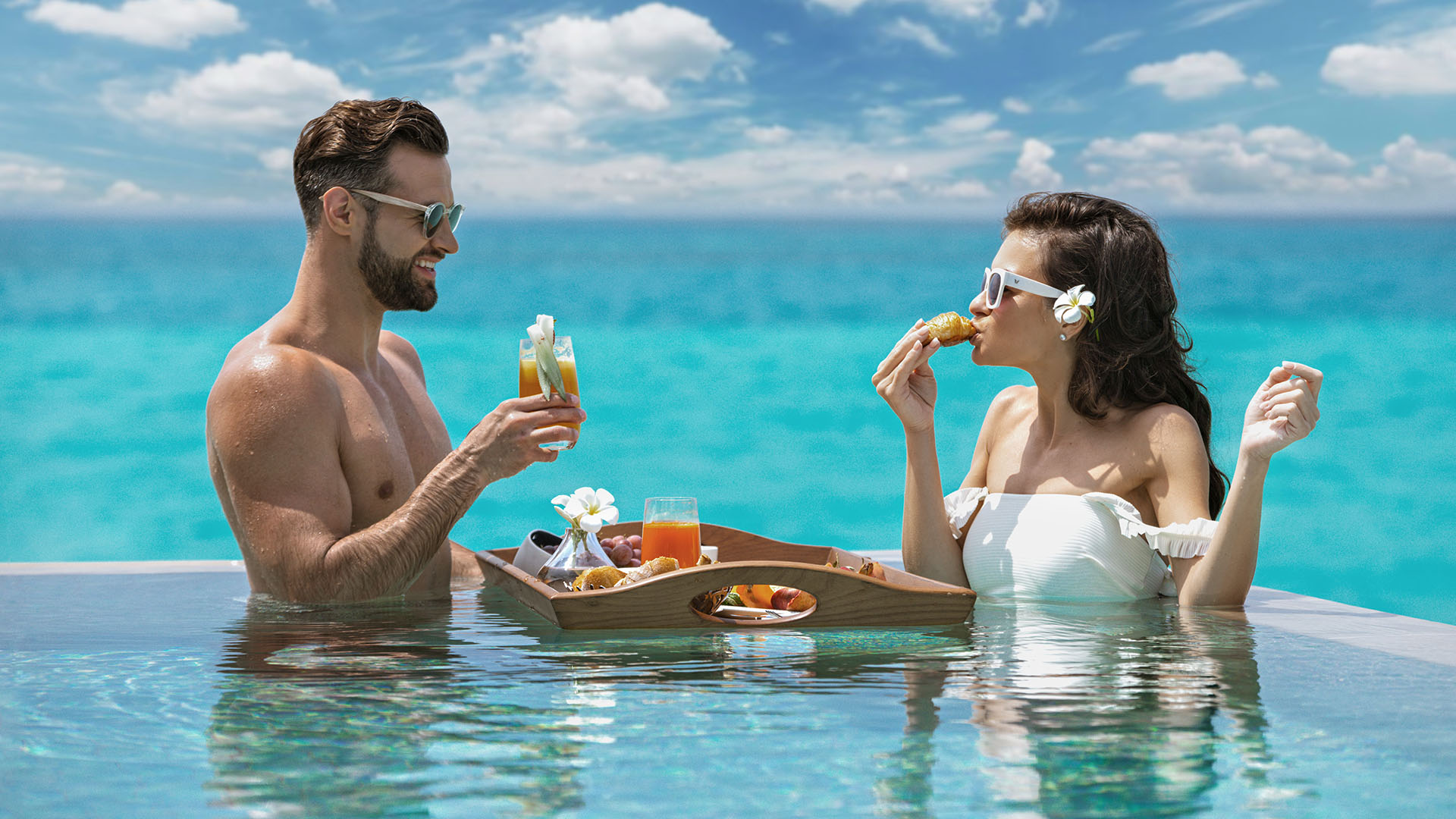 Couple enjoying a food platter in a pool at Kuda Villingili Maldives