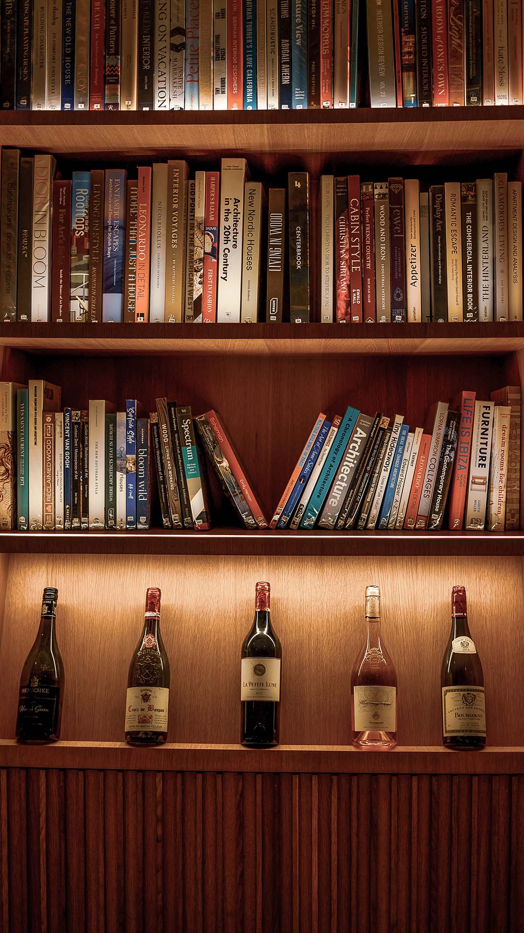 Books and wine bottles neatly arranged on a shelf in Kuda Villingili’s library