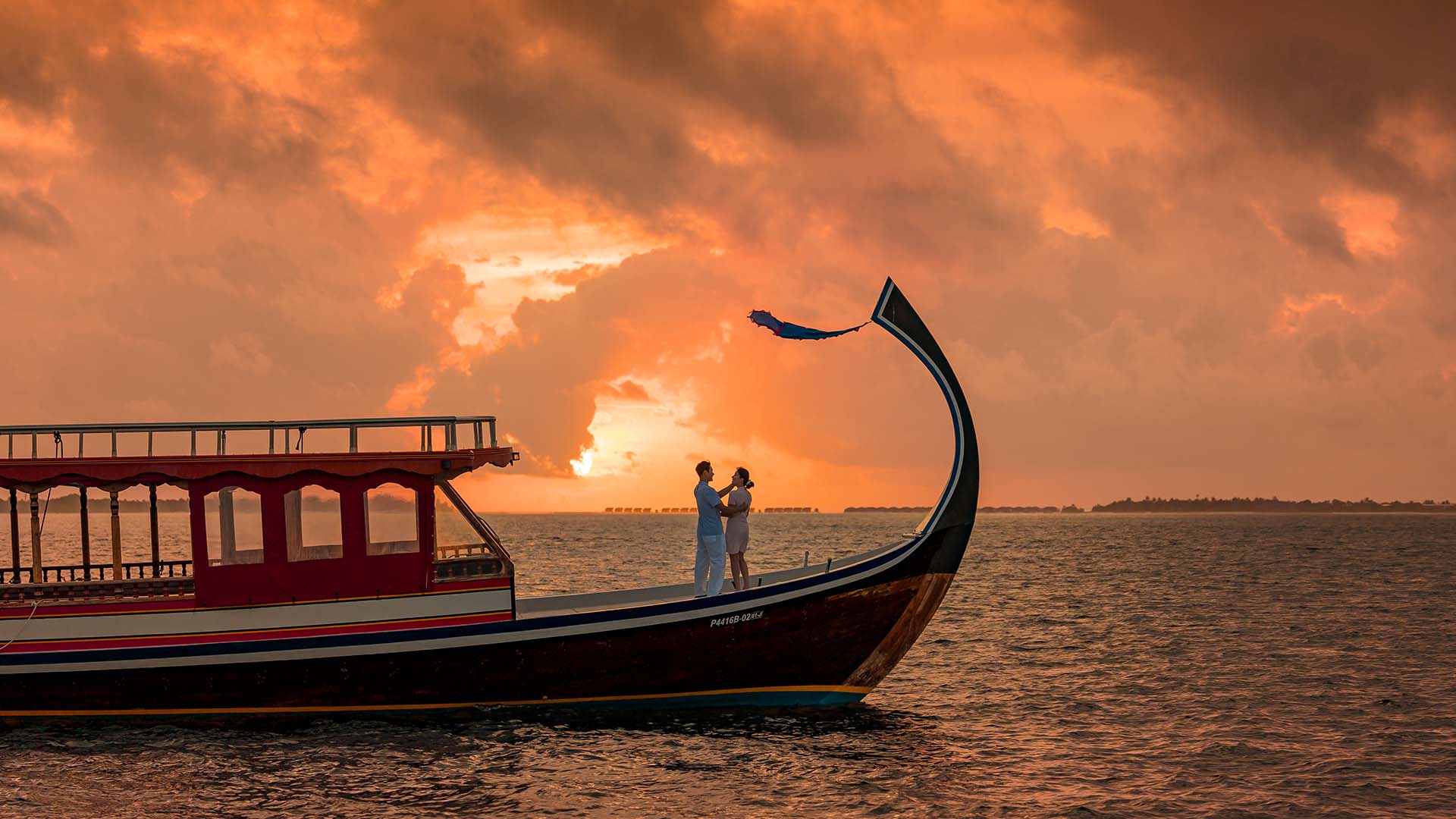 Couple sharing a romantic moment on a sunset cruise at Kuda Villingili
