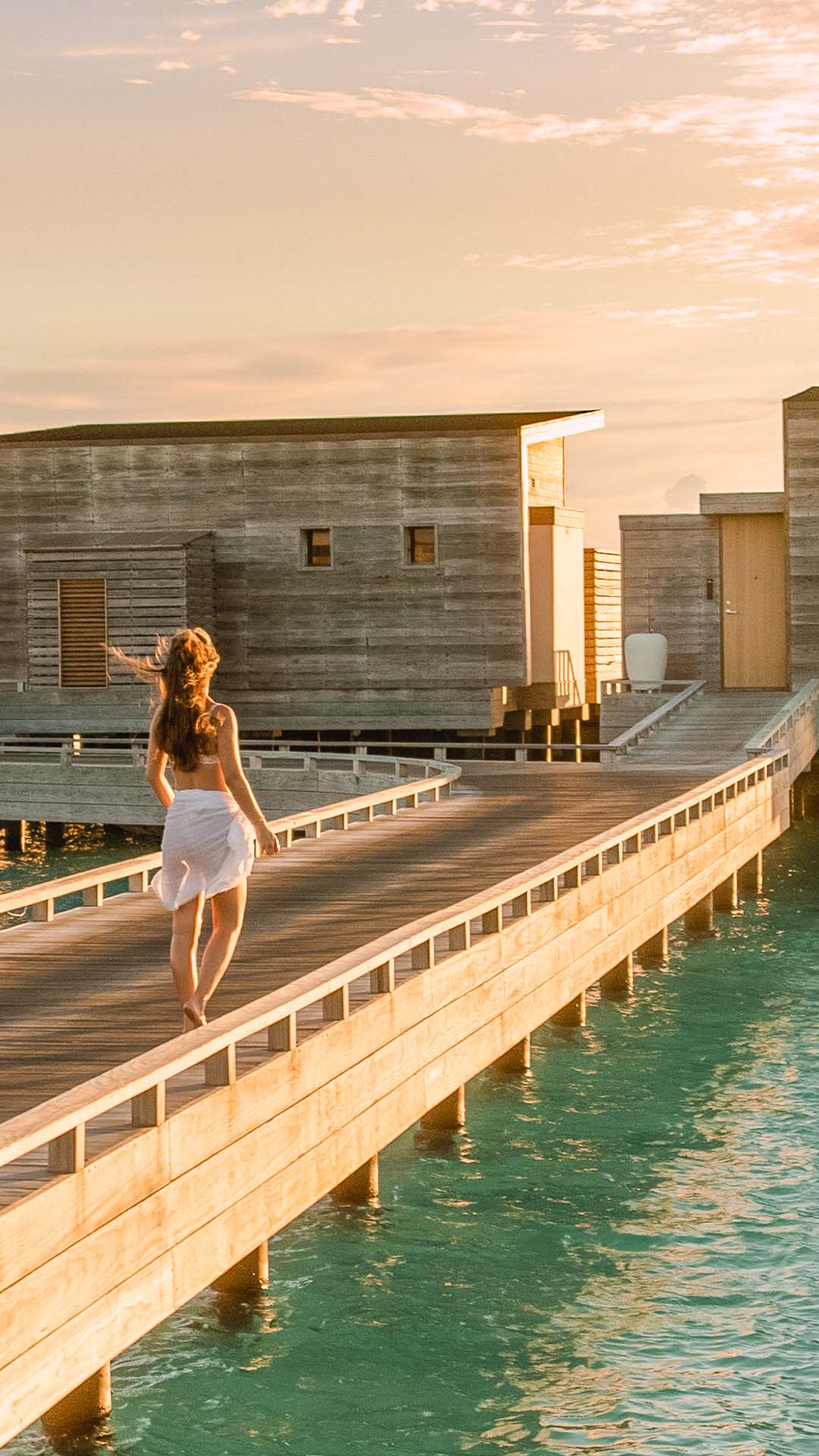 Girl strolls on a wooden bridge in Kuda Villingili Maldives