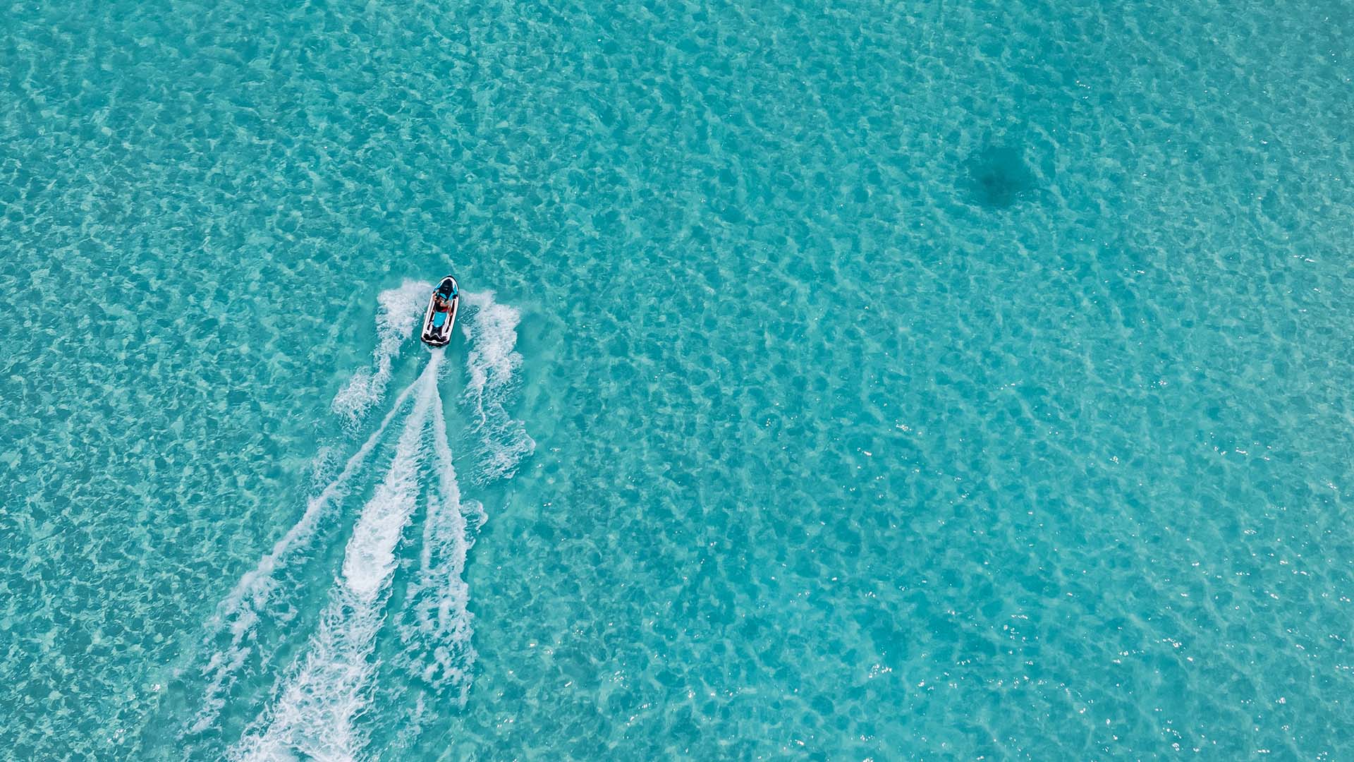 Aerial view of a boat ride on crystal-clear waters in Kuda Villingili
