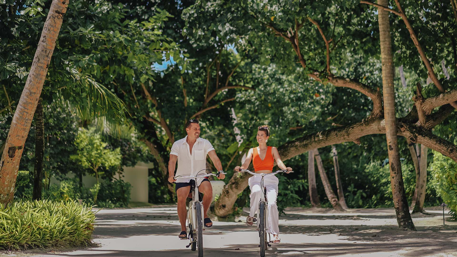 A couple rides bicycles along a scenic path in Kuda Villingili