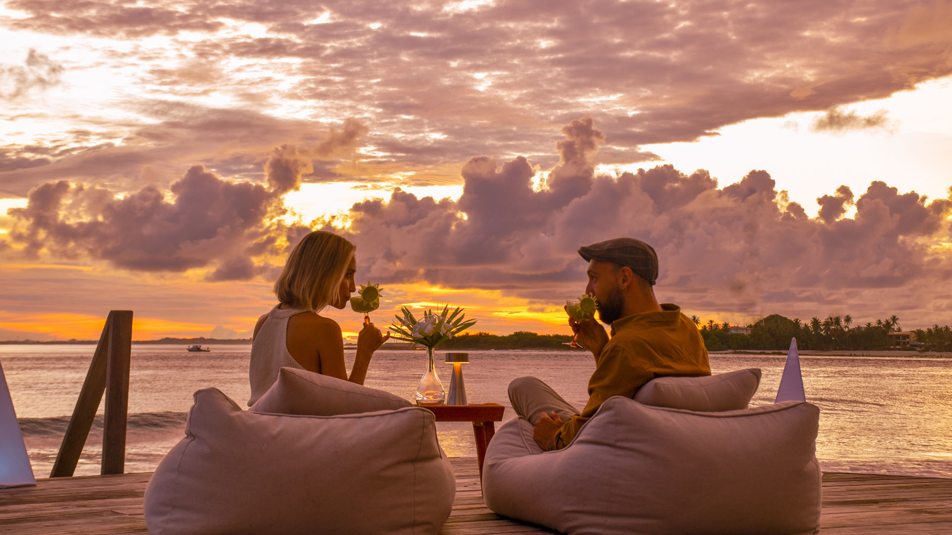 Couple enjoying drinks at sunset on a deck in Kuda Villingili Maldives
